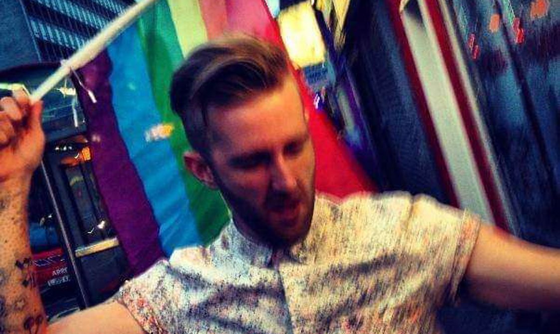 Kerry waving a Pride flag on the street at the 2014 London Pride.