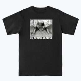 Black and white Image of someone's feet with boots on and spikey shackles around their ankles. On a black T-shirt from the UK Fetish Archive Merch.