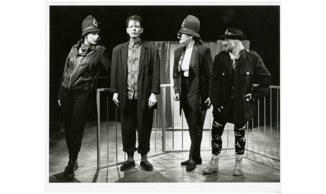A black and white image of four performers, three of which are are wearing police hats.