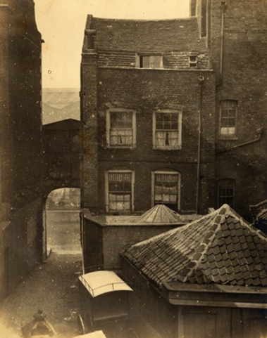 A sepia photo of the site purchased that became Bishopsgate Institute. It is a narrow townhouse, with an archway next to it.