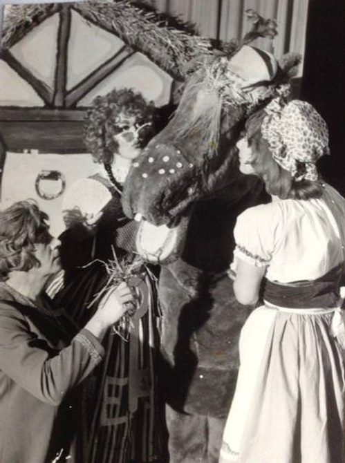 A black and white image of performers feeding a prop horse. Image is from our Clean Break archive collection.