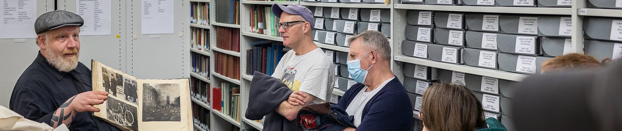 Image of Stefan Dickers holding a book open, while giving a tour of the archives.