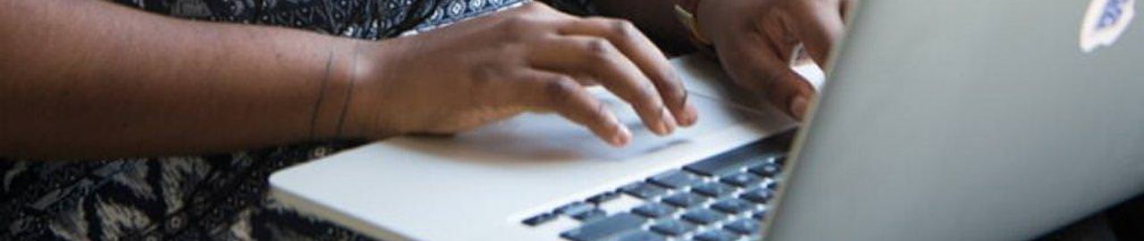 A woman is typing on a laptop. The image focuses on her hands and the keypad.