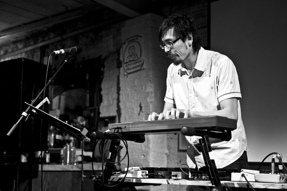 Performer Kerry Young is playing the keyboard on stage, with a microphone in front of him.