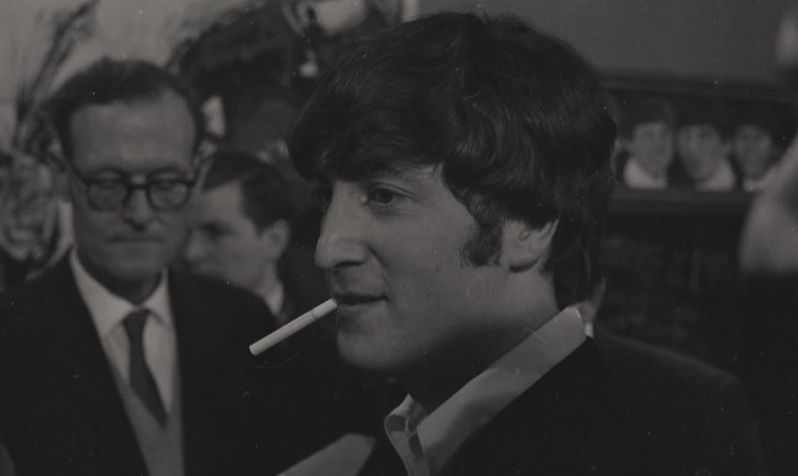 A black and white photo of the Beatles being interviewed.
