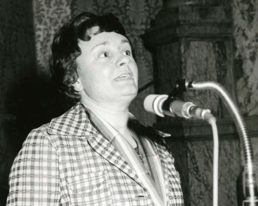 Black-and-white photograph of Christine Walker speaking at an event