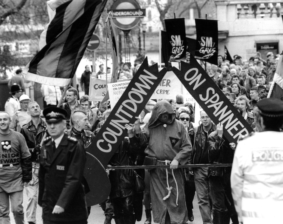 SM Pride March on 28 November 1992. Protestors are holding a banner that says "Countdown on spanner" with a police officer ahead of the protestors.