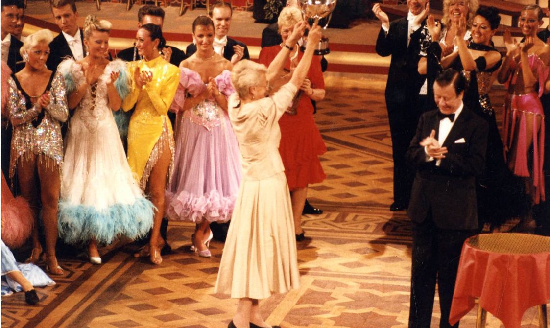 Peggy Spencer holding a trophy, surrounded by dancers, in Blackpool in 1990.