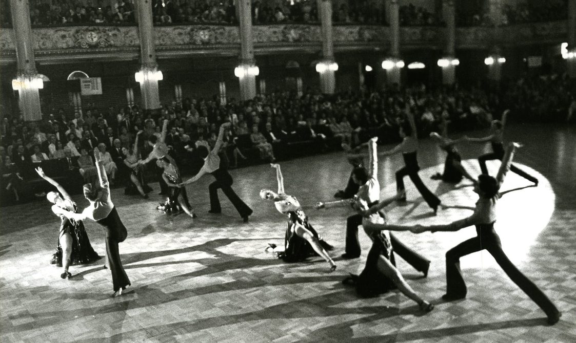 Dancers performing at Royal Albert Hall. They are on the dance floor with an audience surrounding them.
