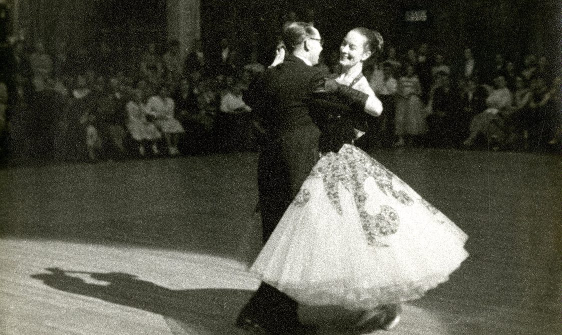 Peggy Spencer and her husband Frank dancing on a ballroom floor, with people watching them.