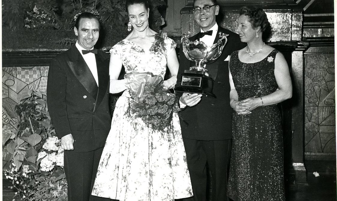 Peggy Spencer standing next to three people, being awarded a trophy at Blackpool.