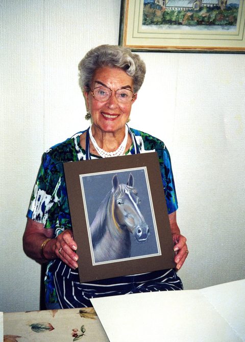 An image of Peggy Spencer holding up a photograph of a horse.