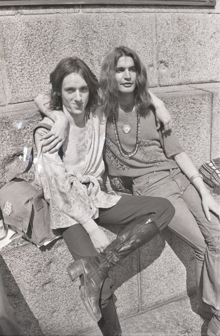 A picture from the second Pride march in 1973. Two people are sitting down on the steps at Embankment, with their arms wrapped around each other.