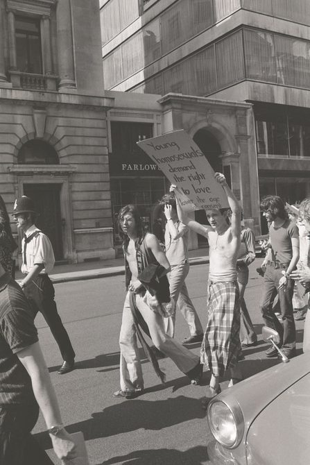 A picture from the second Pride march in 1973. A group of people are marching down from Embankment to Hyde Park. In this image, one person is holding a sign that says: "Young homosexuals demand the right to love".