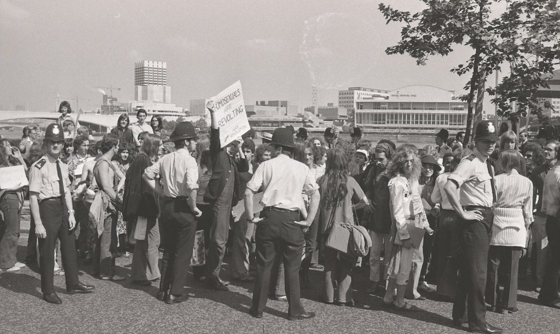 A picture from the second Pride march in 1973. A group of people are marching down from Embankment to Hyde Park. Police officers are standing by the protestors.