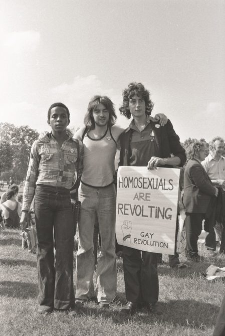 A picture from the second Pride march in 1973. Three men are standing next to each other, including Ted Brown and Peter Tatchell. Peter is holding a sign that says: "Homosexuals are revolting".