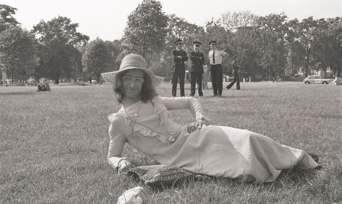A picture from the second Pride march in 1973. This photo is of someone lying on the grass in Hyde Park wearing a dress and sunhat.