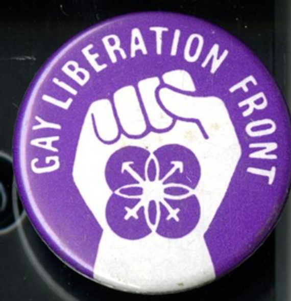 A purple Gay Liberation Front badge with a white fist in the middle and white writing that says: "Gay Liberation Front".