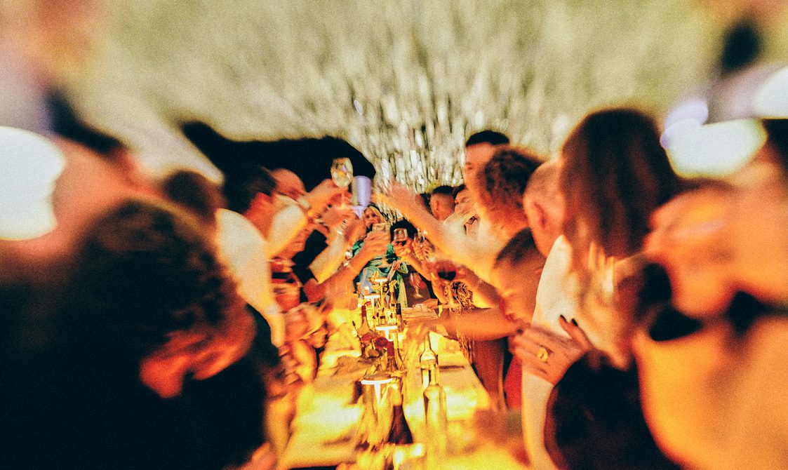 Guests at a long table toast during a wedding ceremony