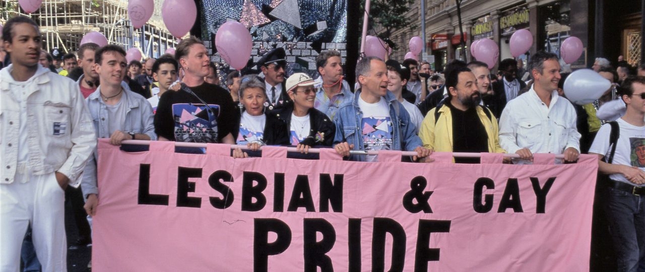 People carrying the lead banner of the Lesbian & Gay Pride parade from 1990, at the front of the march.
