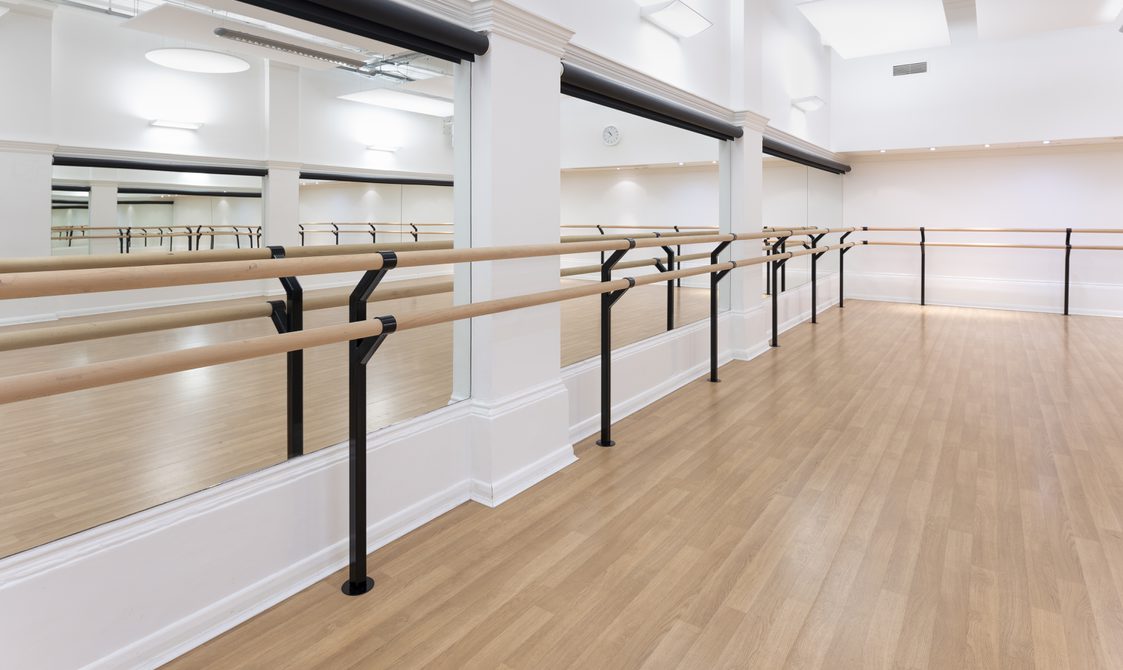 A photograph of Bishopsgate Institute's studio in Central London. There are full length mirrors on the floor and a bar going around the room.