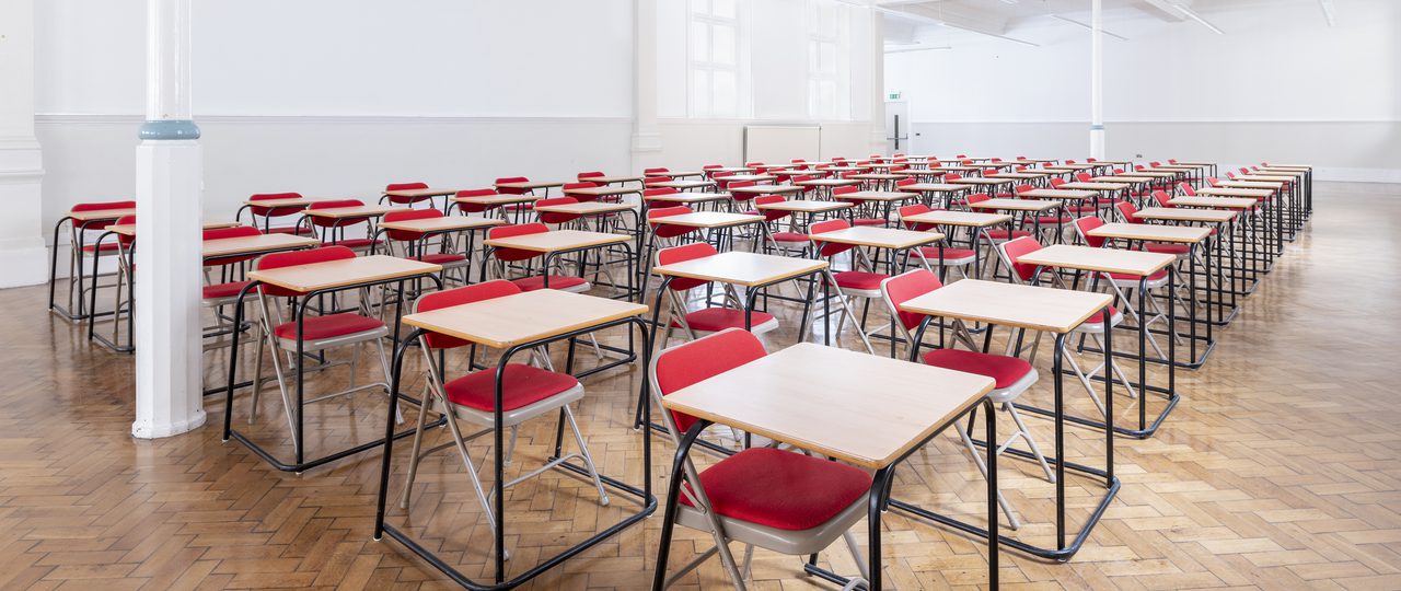 Rows of single tables with chairs are laid out in Bishopsgate Institute's Upper Hall in an examinations style.