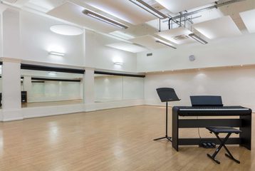 A picture of Bishopsgate Institute's studio. There is a keyboard and stool in the corner. The walls are mirrored.