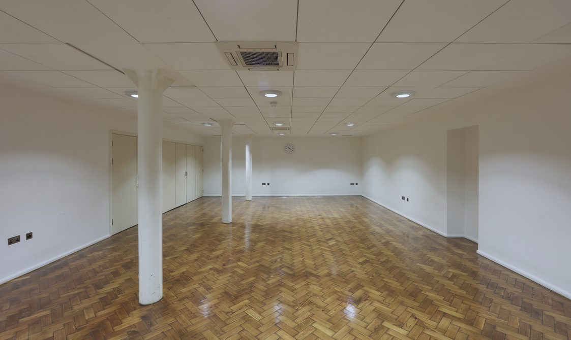 A photograph of the Goss Room. The floor is laminated and the walls are white with skylights.