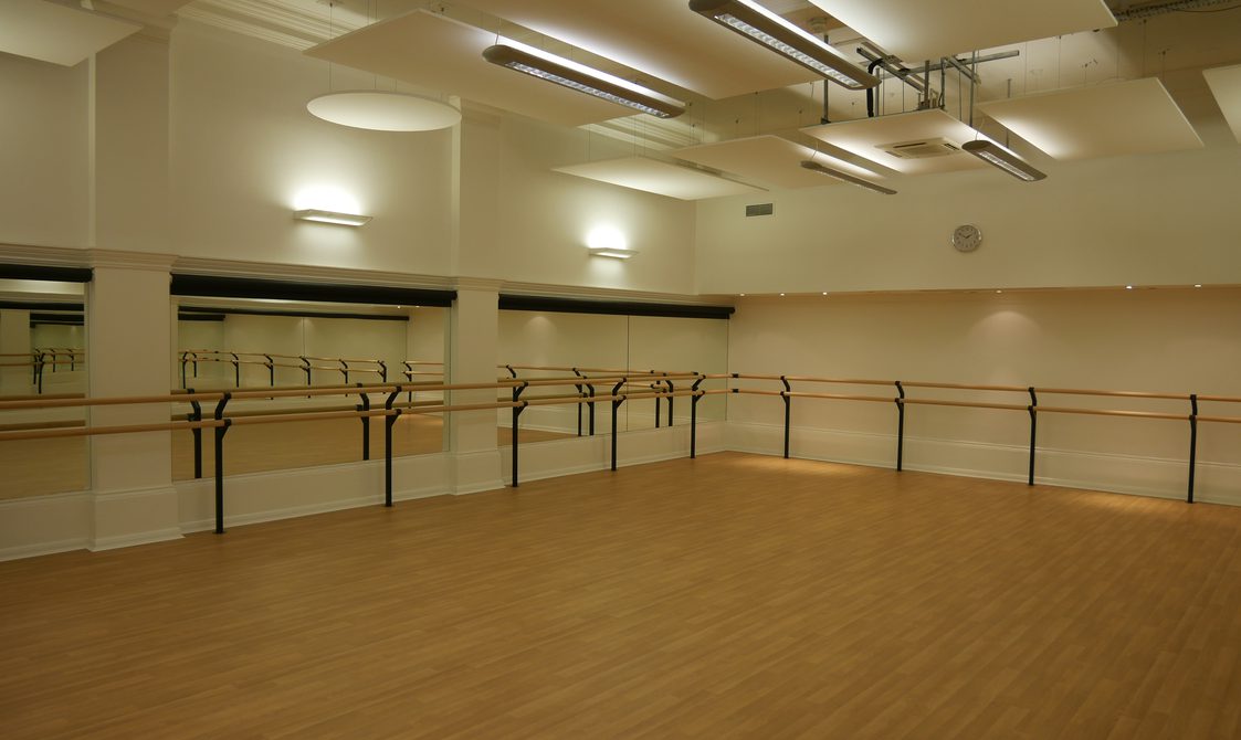 A photograph of the studio at Bishopsgate Institute. The floors are wooden with white walls. There are mirrors on the walls and dance bars around the sides.
