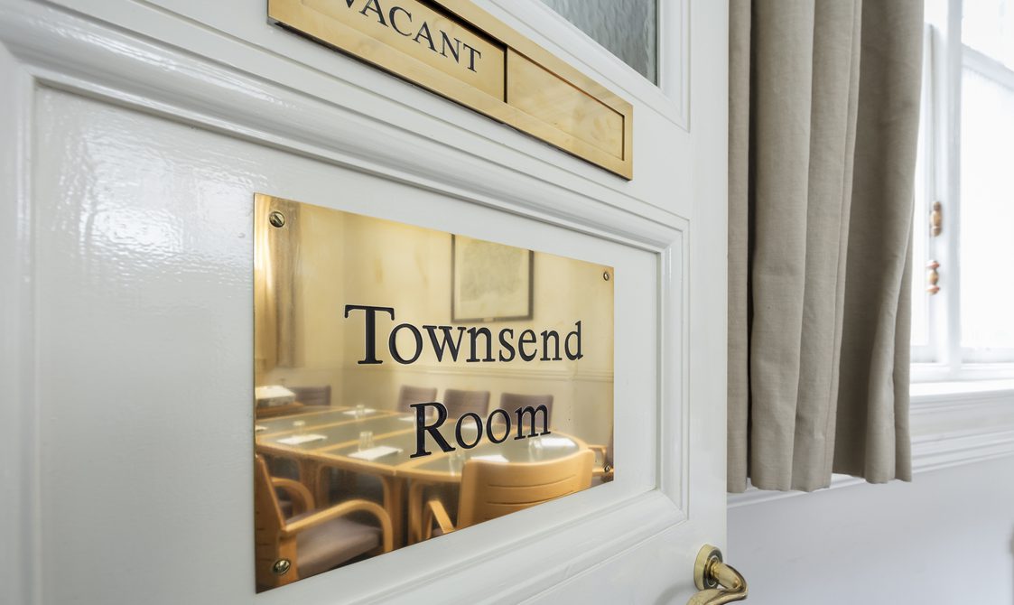 A white door with a gold sign that says in black writing "Vacant", and underneath is another gold sign that says: "Townsend Room".