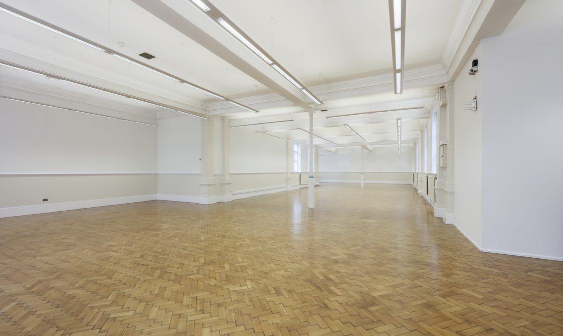 A photograph of the Upper Hall with natural light coming through. The floor is laminate, and the walls are white.