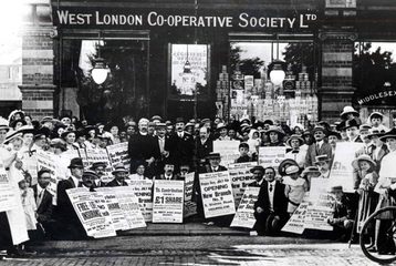 Black and white image of people standing in front of the West London Co-operative Society with signs