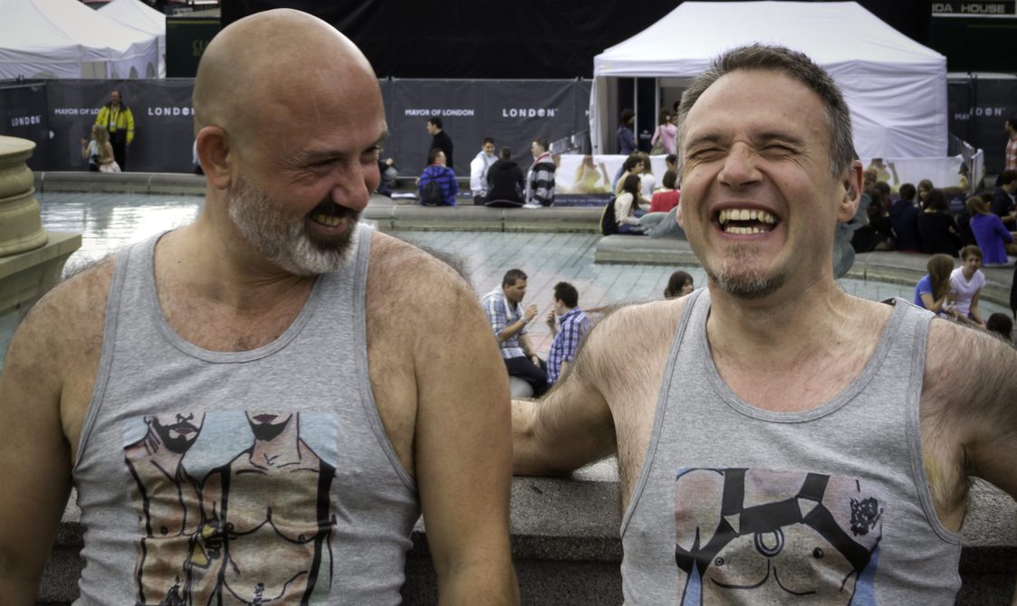 Cliff stood with his friend Alexandre, posing to show off the t-shirts designed by Alexandre. They have made each other laugh and they can't get a straight face.