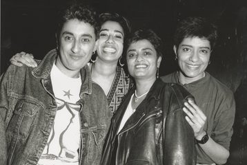 A black and white picture of four South Asian women looking at the camera and smiling