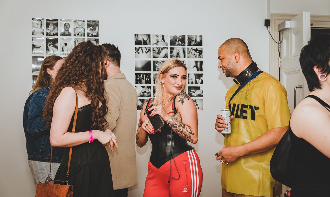 Artistic duo The London Vagabond together with members of the public standing in front of a photography display.
