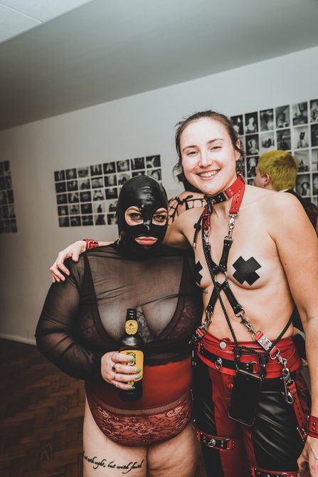 Two people dressed in fetish wear. They are looking directly at the camera and one has their arm around the other.