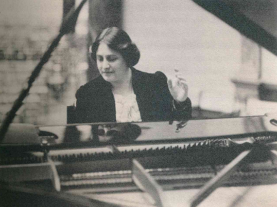 Black and white image of Myra Hess sat at her piano.