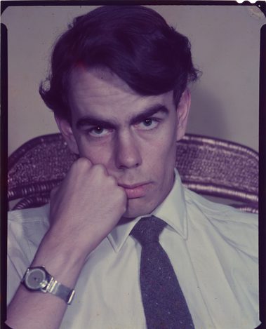 Self-portrait of photographer Derek Brook. He is resting his face on his fist, looking a little sullen.