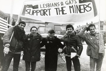 Members of Lesbians & Gays Support The Miners, stood outside in winter with a large banner protesting